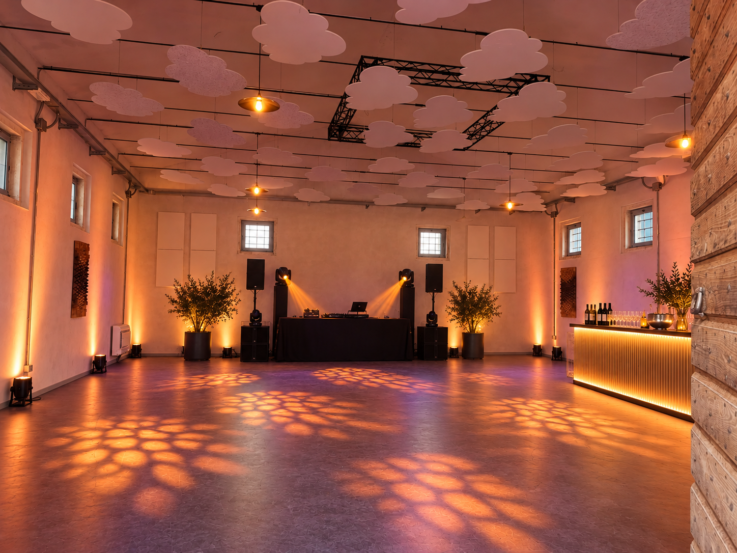 Sala eventi con DJ, bar illuminato e luci calde